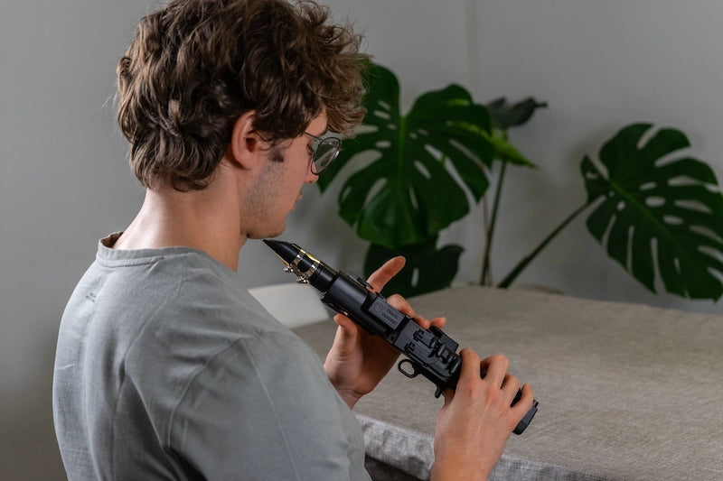 A player practising the Travel Clarinet at a table with headphones on, the instrument plugged into Odisei Play.